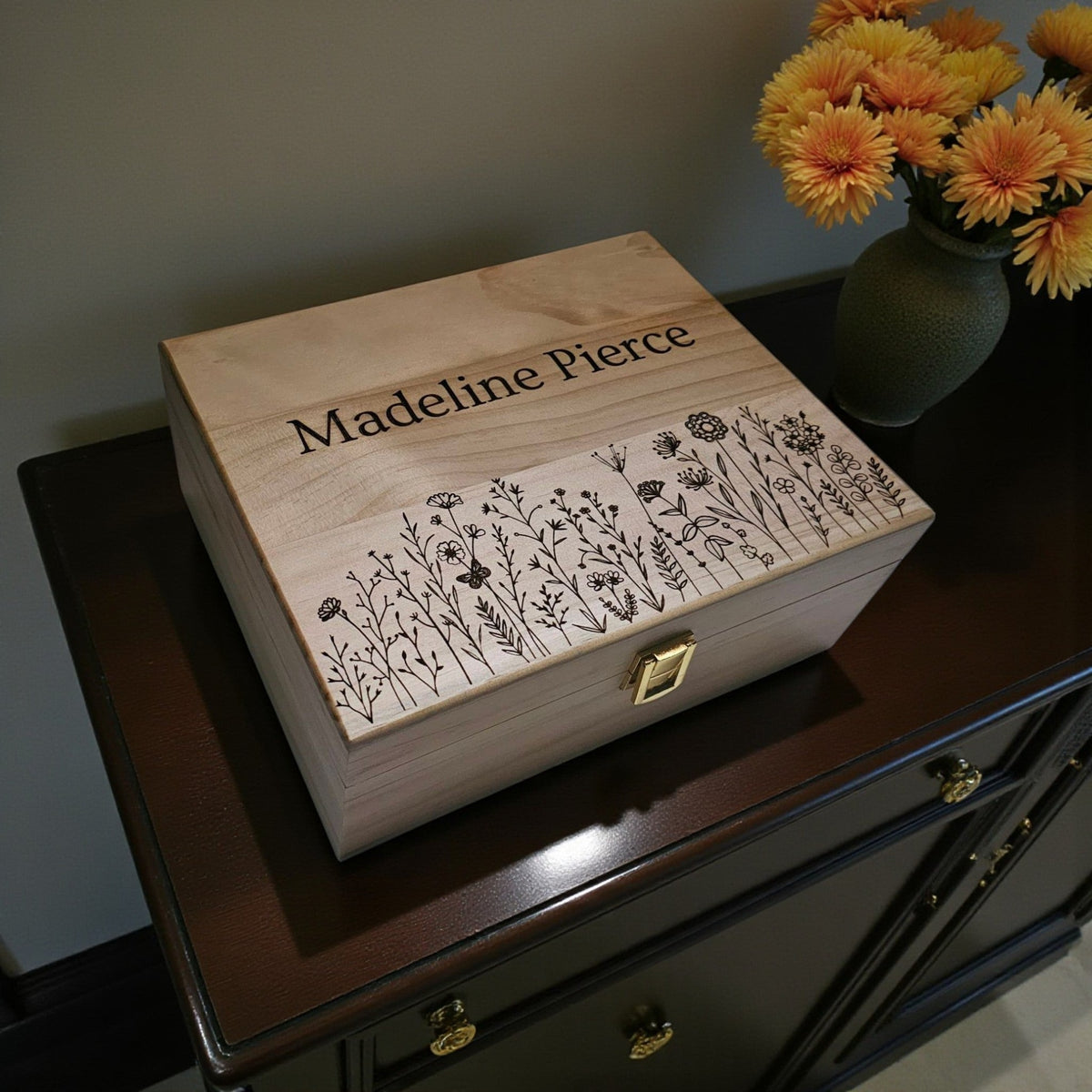 Newfashioned Relics personalized wooden keepsake box with engraved wildflower design and name on a dark wood dresser.