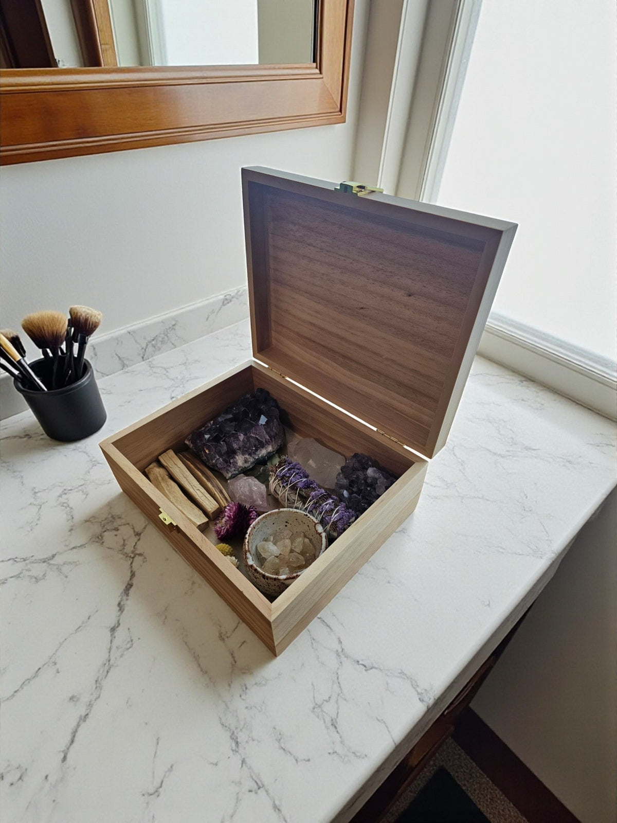 Newfashioned Relics wooden keepsake box filled with crystals, sage, and palo santo on a marble countertop.